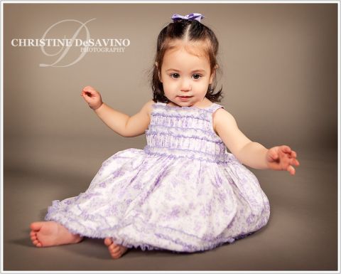 Studio portrait of a sweet little girl in a beautiful purple flowered dress